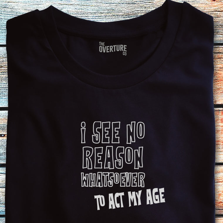 Black t-shirt with the statement ‘I See No Reason Whatsoever To Act My Age’ in bold white text, ideal for those with a playful attitude.